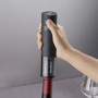 Black electric corkscrew in use on a bottle of wine